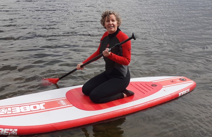 kneeling to balance a paddleboard