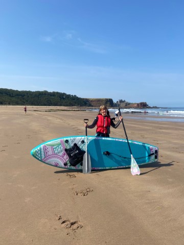 standing at the beach with paddleboard ready to go open water paddleboarding