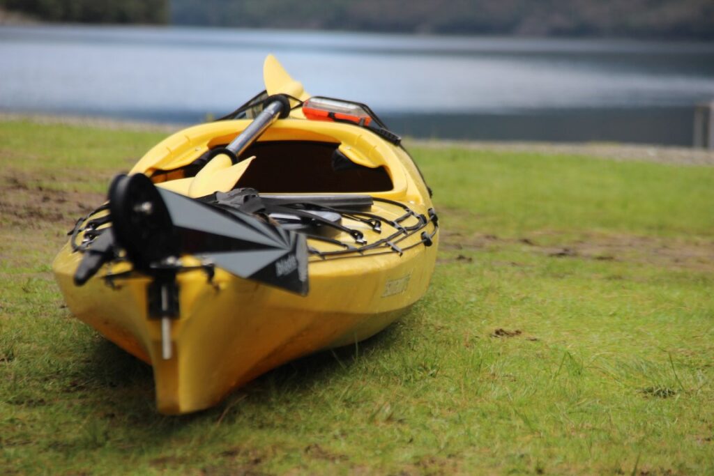 yellow kayak sitting on dry land alongside water